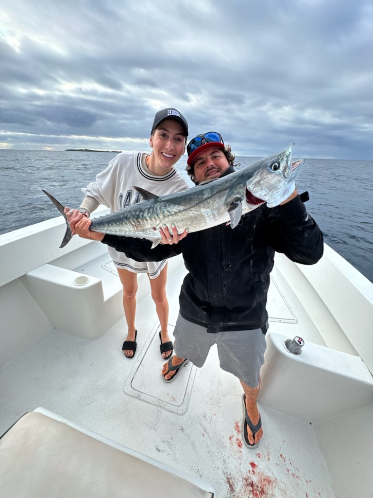 Couple holding a kingfish at sunrise aboard Top Shot