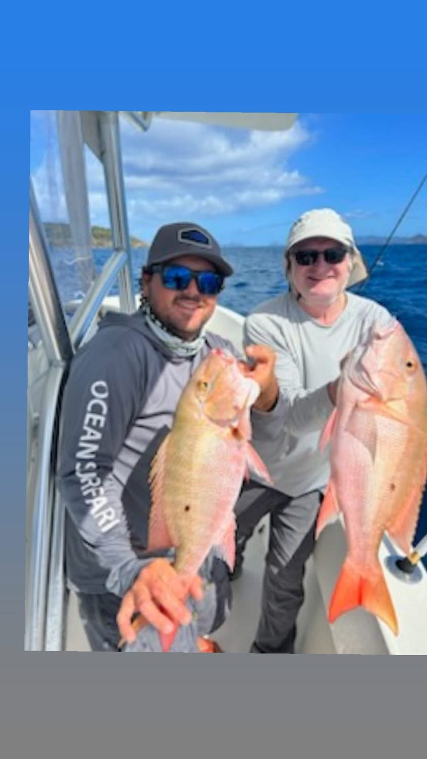 Two anglers holding a pair of bright red snapper aboard Top Shot