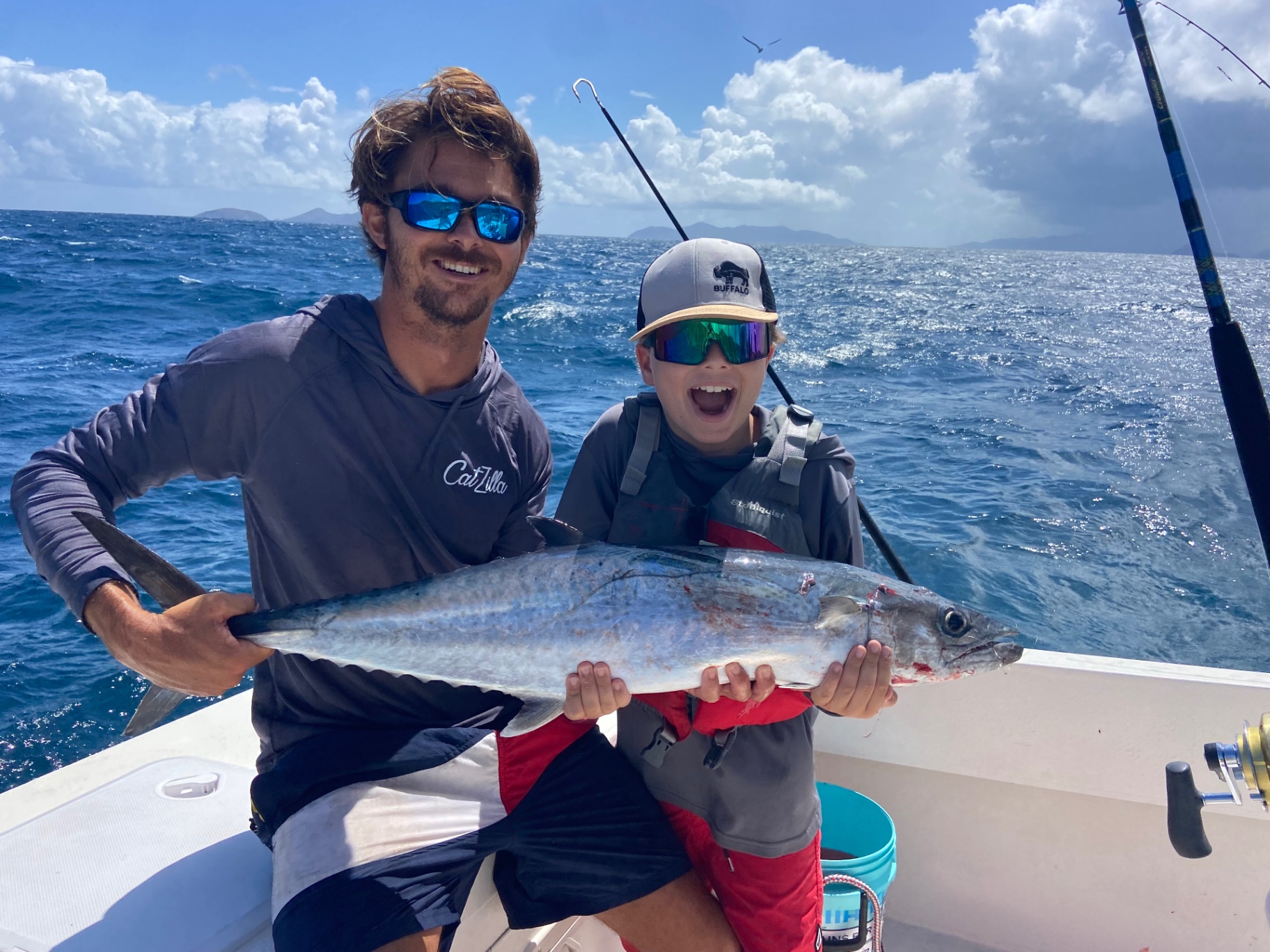 Young angler and mate holding a kingfish offshore